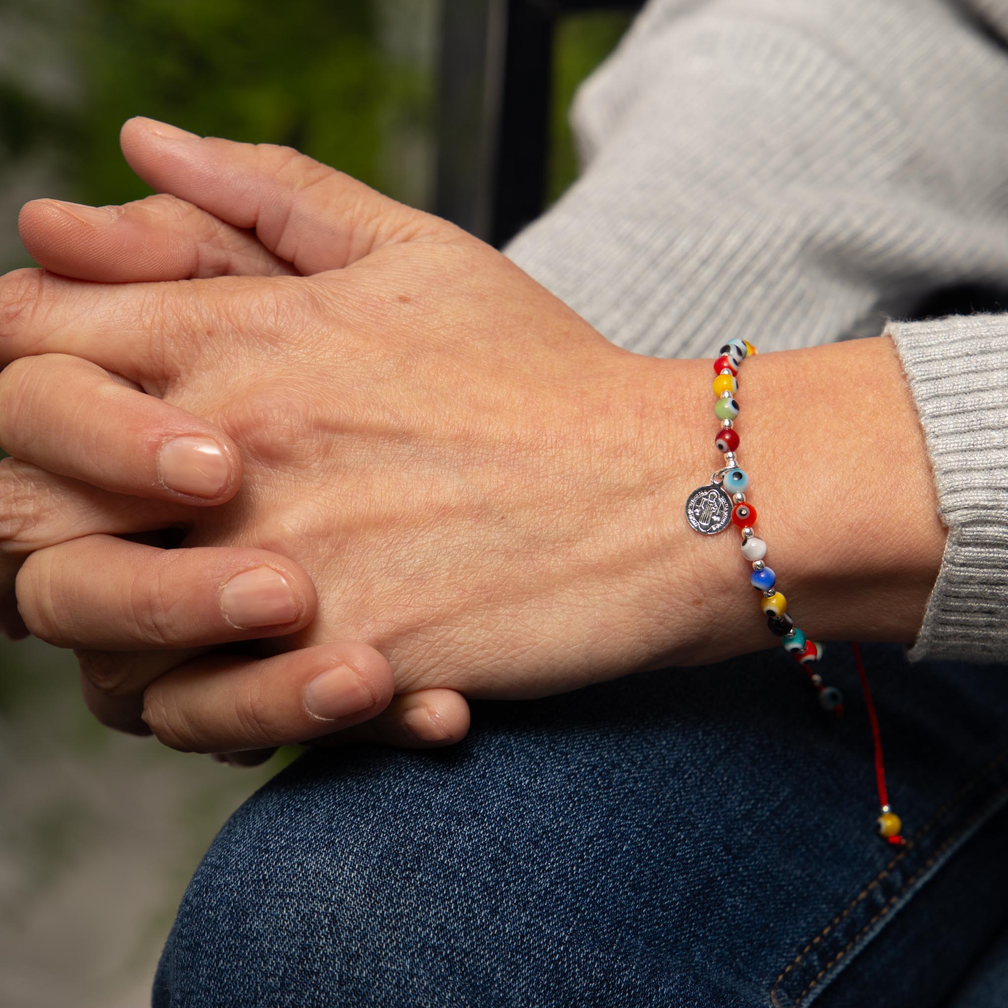 Pulsera de hilo con dije de San Benito de plata y ojos turcos